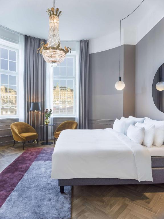 a bedroom with a large white bed and a chandelier at Radisson Collection, Strand Hotel, Stockholm in Stockholm
