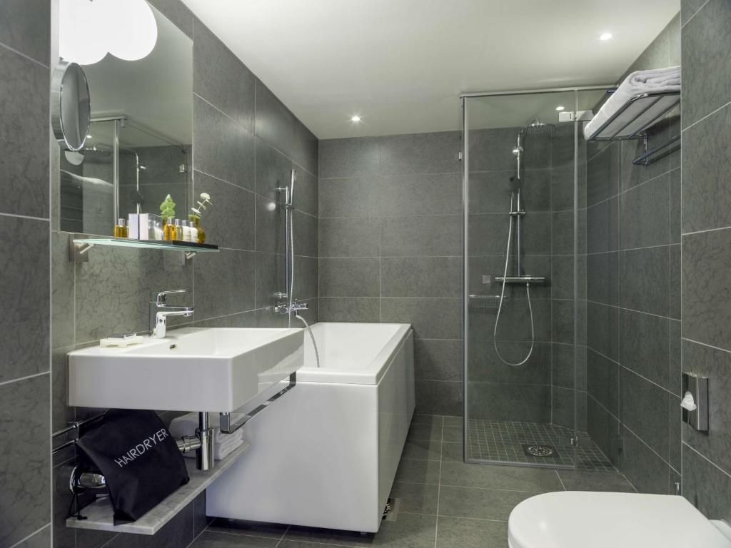 a bathroom with a sink and a shower and a toilet at Radisson Collection, Strand Hotel, Stockholm in Stockholm