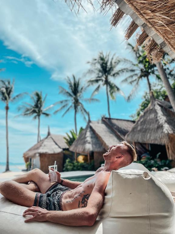 a man laying on a chair on the beach at Sea Love Beach Bar & Bungalows in Ban Tai