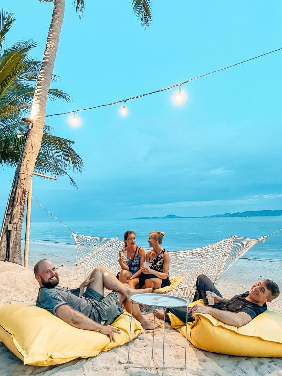 a group of people laying in a hammock on the beach at Sea Love Beach Bar & Bungalows in Ban Tai