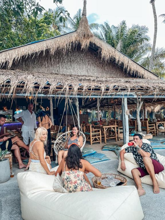 a group of people sitting on a couch in front of a hut at Sea Love Beach Bar & Bungalows in Ban Tai