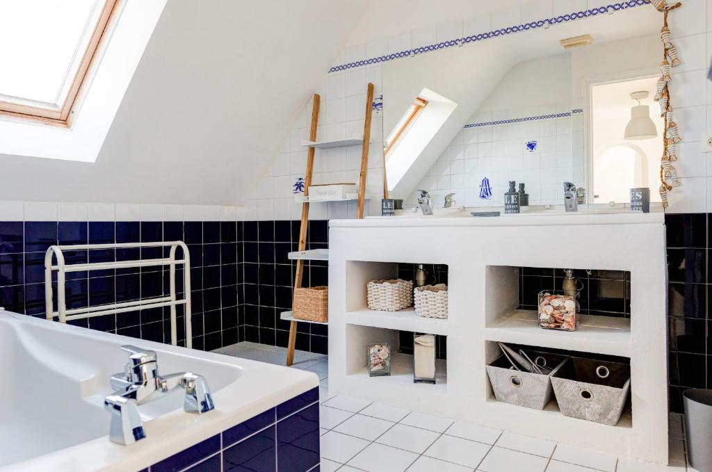 a bathroom with a sink and a blue tiled wall at Belle maison pour les amoureux de la mer dans le Finistere in Plomeur