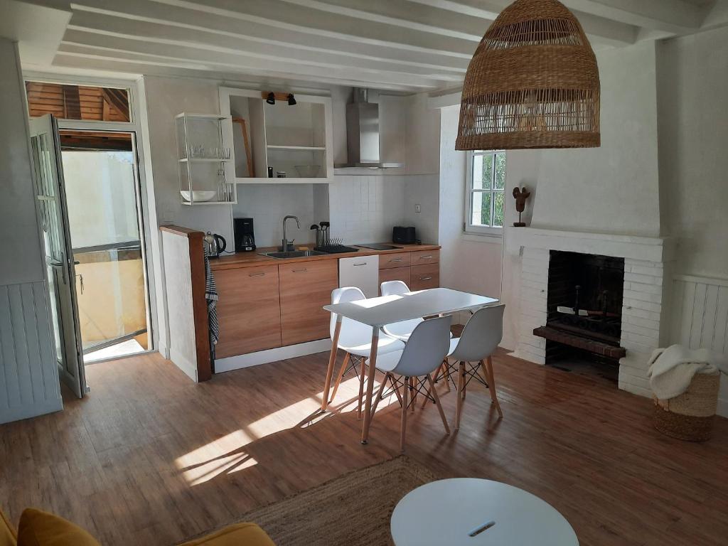 eine Küche mit einem Tisch und Stühlen sowie einem Kamin in der Unterkunft Maison avec jardin dans petit bourg typiquement Percheron - Le Colombier in Boissy-Maugis