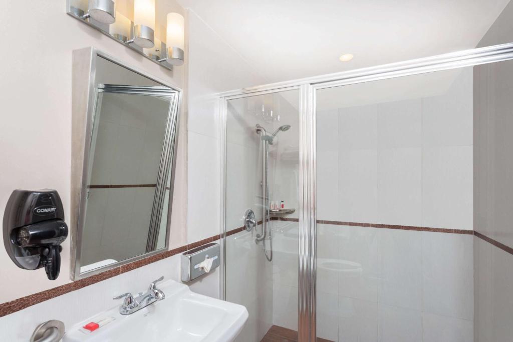 a white bathroom with a shower and a sink at Ramada by Wyndham Miami Springs/Miami International Airport in Miami