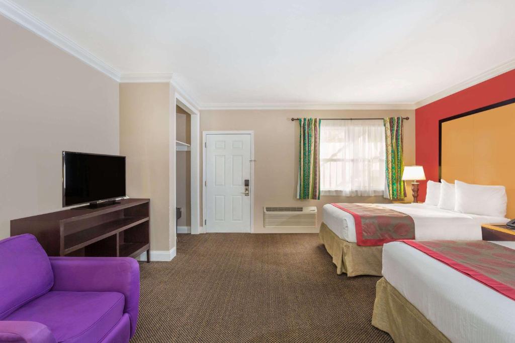 a hotel room with a bed and a couch and a tv at Ramada by Wyndham Miami Springs/Miami International Airport in Miami