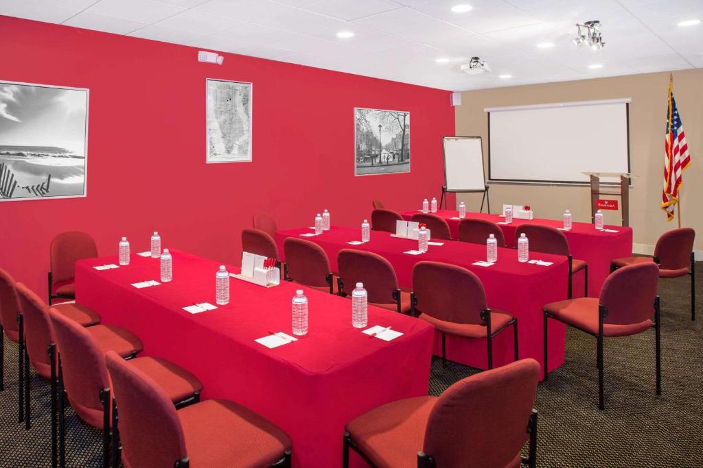 a conference room with red walls and red tables and chairs at Ramada by Wyndham Miami Springs/Miami International Airport in Miami
