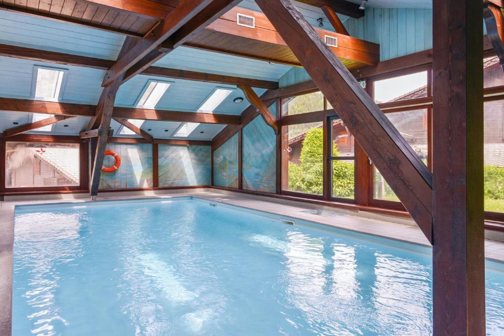 une grande piscine intérieure avec des plafonds en bois et des fenêtres. dans l'établissement Appartement chaleureux à Les Houches 29 m² avec piscine partagée, aux Houches