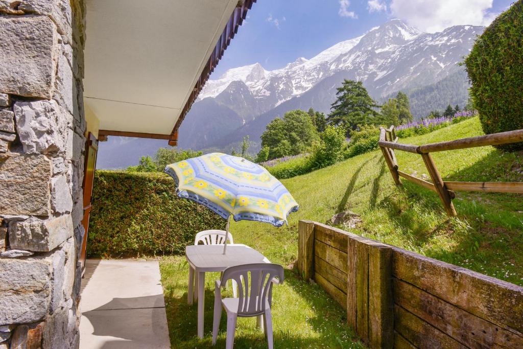 een tafel en twee stoelen met een paraplu bij Appartement d'une chambre a Les Houches a 30 m des pistes avec piscine partagee et jardin amenage in Les Houches