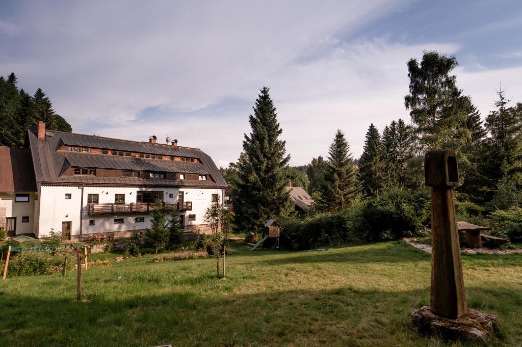 a large white building in a field next to a forest at Pension Styl in Bedřichov