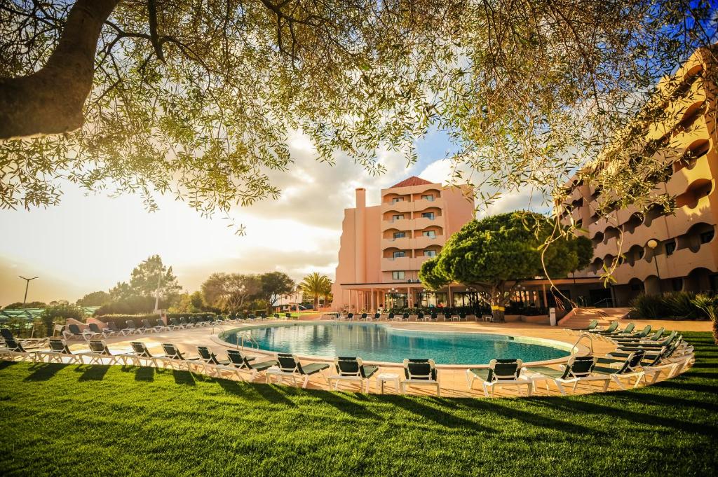 ein Schwimmbad mit Stühlen und ein Gebäude in der Unterkunft Vila Gale Atlantico in Albufeira