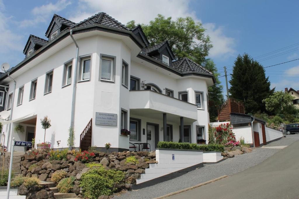 ein weißes Haus mit schwarzem Dach in der Unterkunft Gästehaus Ballmann in Rockeskyll