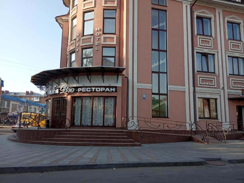 a large pink building with a staircase in front of it at готель ДежаВю in Berdychiv