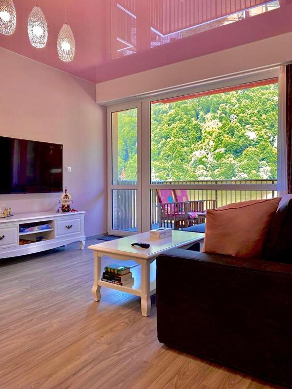 a living room with a couch and a large window at Sweet Pink by Miro Apartment Early Checkin in Sinaia