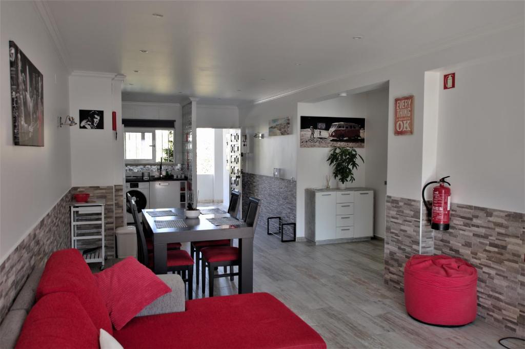 a living room with a red couch and a table at AlbufeiraSun, arrive as a guest leave as a friend. in Albufeira