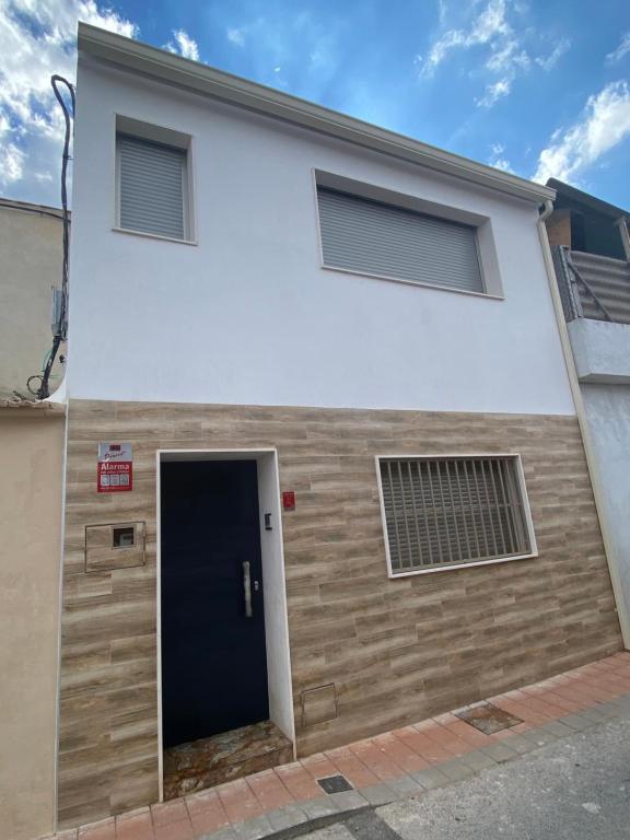 um edifício branco com uma porta preta e duas janelas em CASA SUITE JTG em Alicante