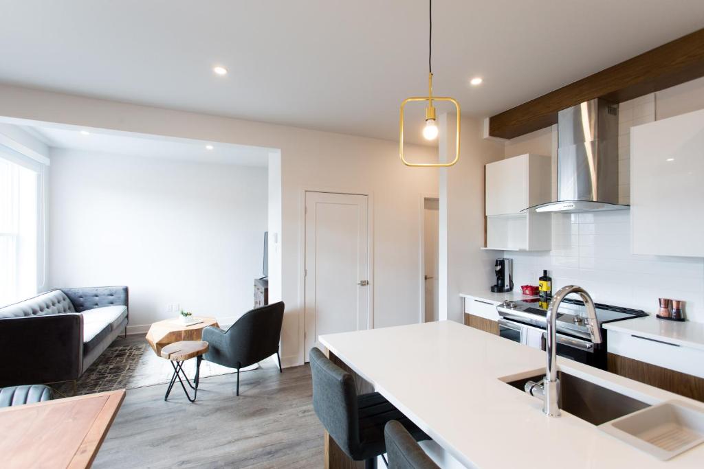 een keuken en een woonkamer met een wastafel en een bank bij Light Filled 2 Bdr Unit in Mile End by Den Stays in Montreal