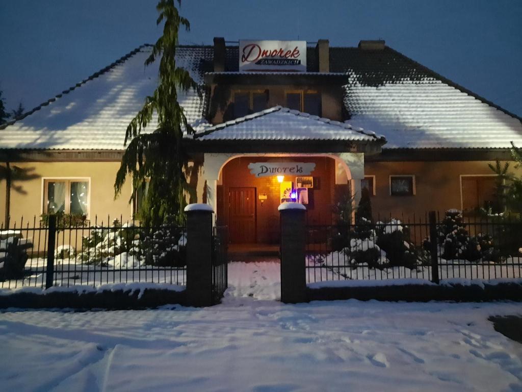una casa en la nieve con un cartel en la puerta en Dworek Zawadzkich, en Kruszyn