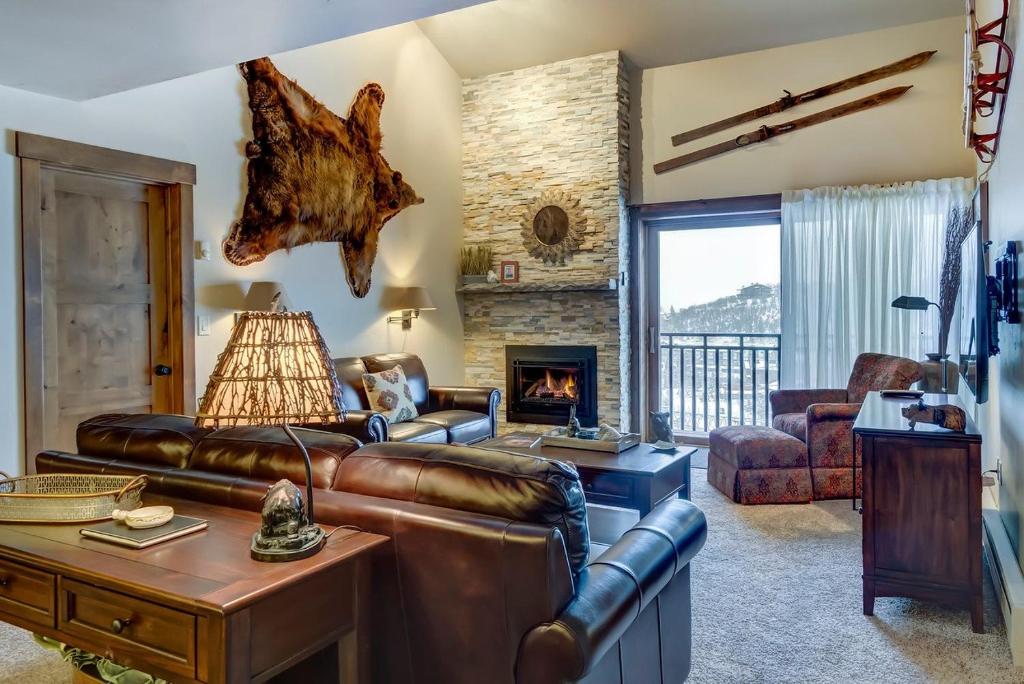 a living room with a leather couch and a fireplace at Bear Claw 508 - True Ski-in Ski-out Access, Slope Views & Winter Shuttle! in Steamboat Springs