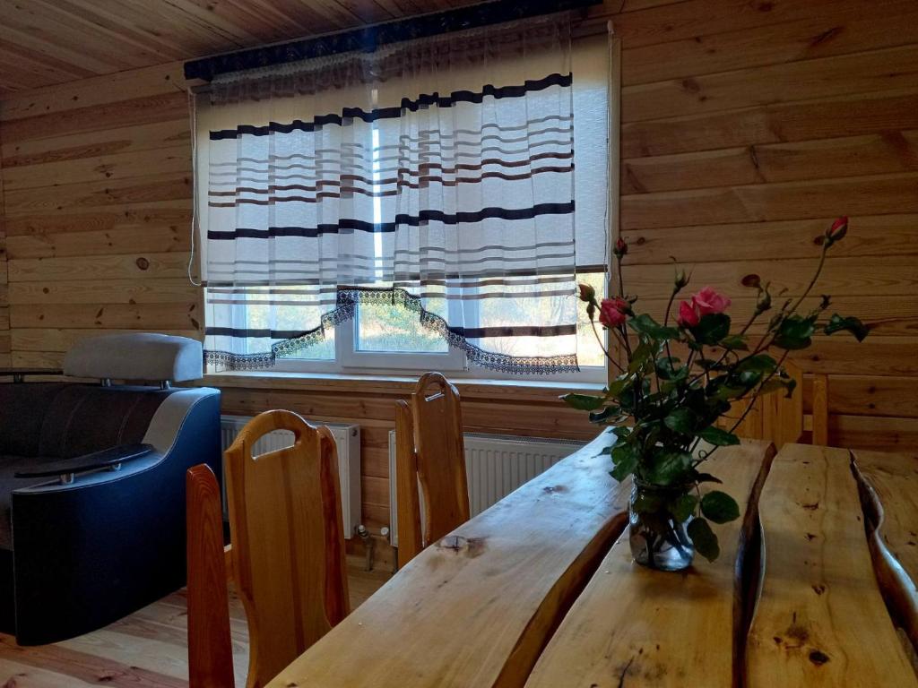 a dining room table with a vase of flowers on it at Плакуча верба in Svityazʼ