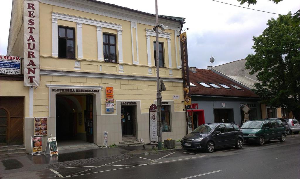 a building on a street with cars parked in front of it at Penzión Marína pri Slovenskej reštaurácii in Brezno