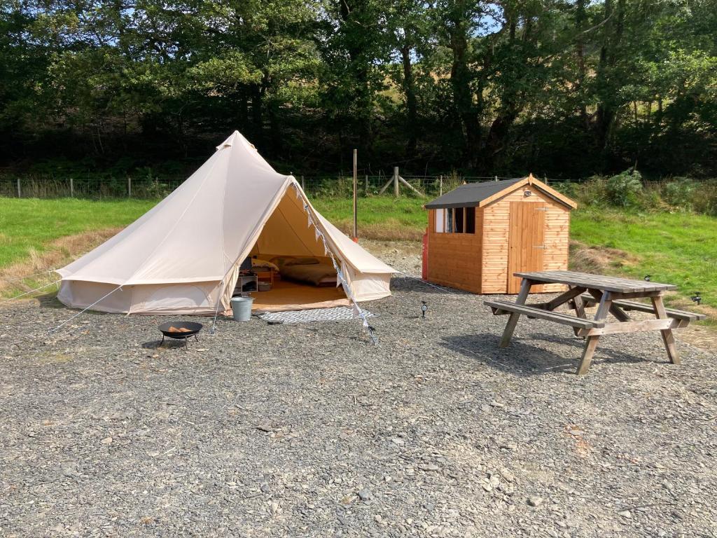 a tent and a picnic table and a bench at Dyfi Dens Machynlleth in Esgair-geiliog