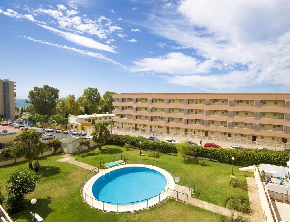 托雷莫利諾斯的住宿－Lovely apartment in Torremolinos Views of the sea, pool, terrace, sofa bed and fully equipped kitchen，一座大型建筑,在一座建筑前设有一个游泳池