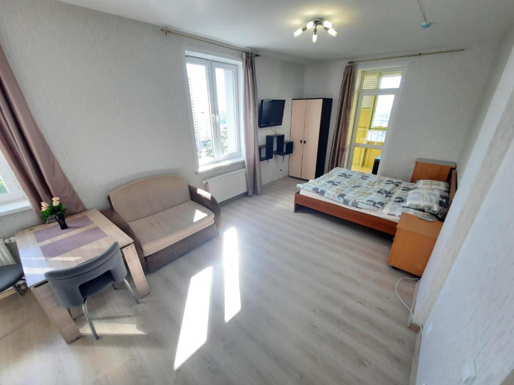 a bedroom with a bed and a chair and a table at K&K Apartments Gulliver 146 in Perm