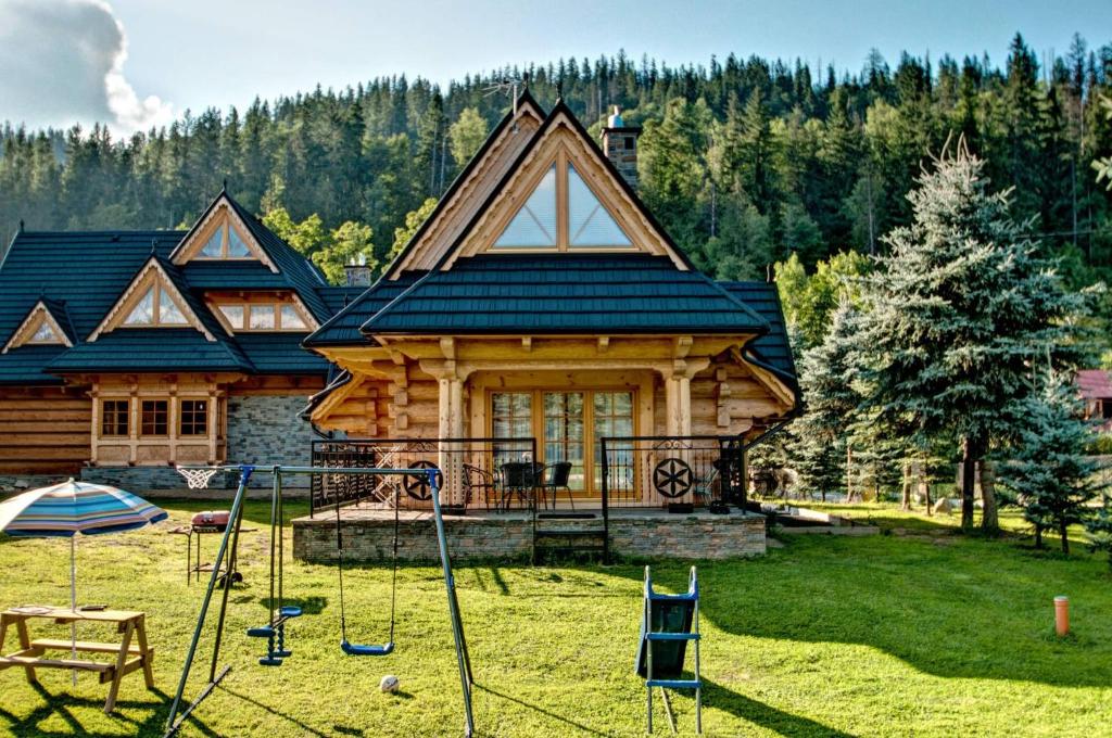 a log house with a playground in front of it at Domek drewniany luxury cottage Dabrowa in Zakopane