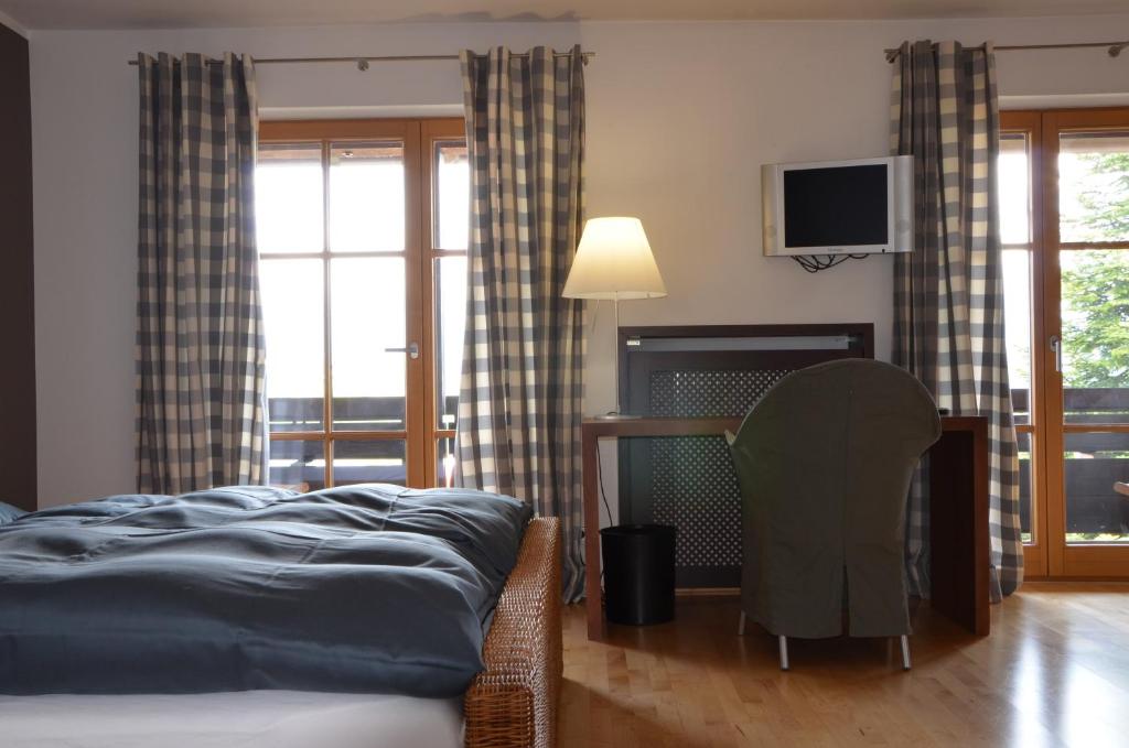 Schlafzimmer mit einem Bett, einem Schreibtisch und einem TV in der Unterkunft Nebelhorn Relaxhotel in Obermaiselstein