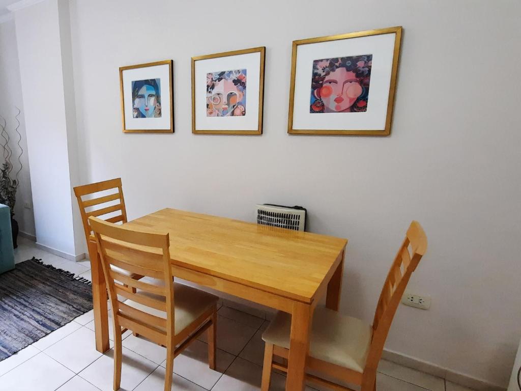 une table à manger avec deux chaises et deux photos sur le mur dans l'établissement Tranquilo, comodo y cerca de todo, à Córdoba