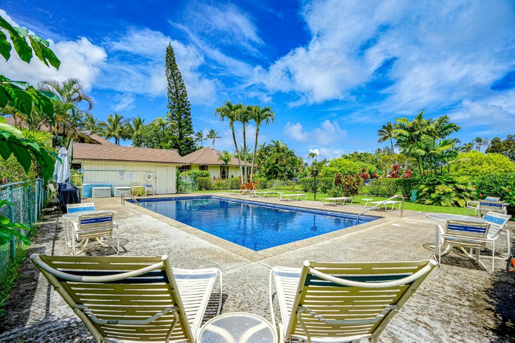 a swimming pool with two lawn chairs next to a house at Paniolo #202B in Princeville