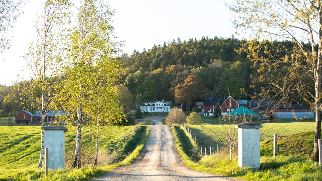 un chemin de terre traversant un champ avec des maisons sur une colline dans l'établissement Hällingsbo Gård, à Lerum