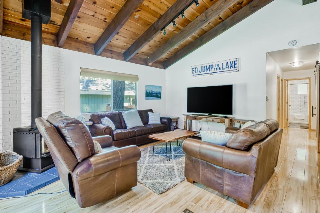a living room with leather furniture and a flat screen tv at The Lazy Golden Cabin in South Lake Tahoe
