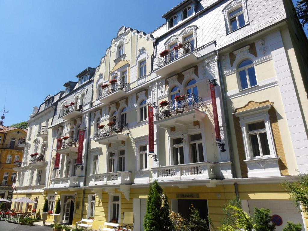 um grande edifício branco com janelas e varandas em Residence Romanza em Mariánské Lázně