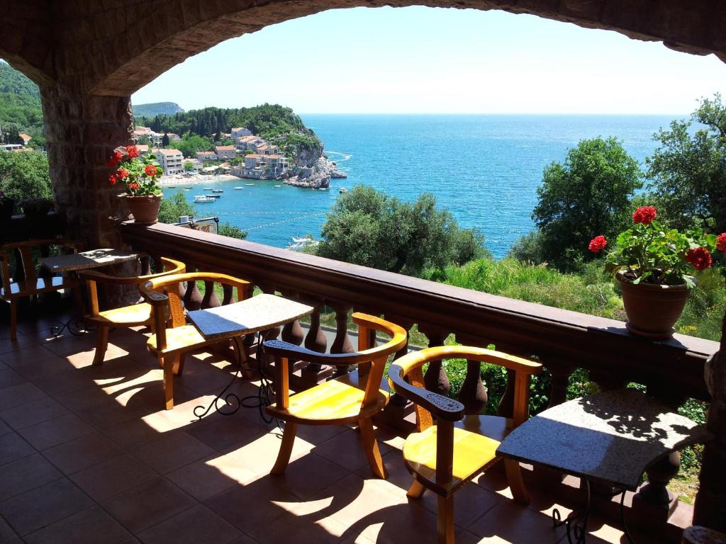 uma varanda com mesas e cadeiras e vista para o oceano em Villa Sara Guesthouse em Sveti Stefan