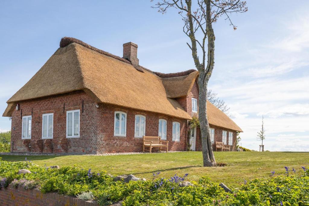 an old brick house with a thatched roof at Reethüs Rosenkranz in Aventoft