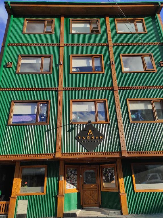 ein grün-weißes Gebäude mit einem Schild darauf in der Unterkunft YAGHAN HOSTEL in Ushuaia