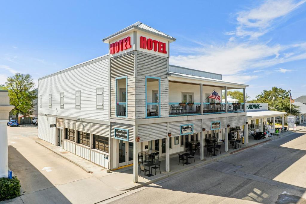 - un bâtiment blanc avec un panneau rouge du motel dans l'établissement Hotel Whiskey in Pass Christian, à Pass Christian