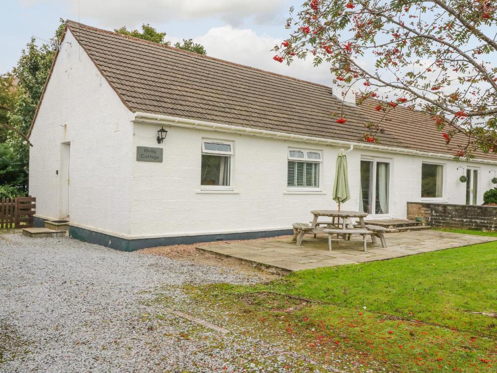 a white house with a picnic table and a patio at Holly Cottage in Glencoe
