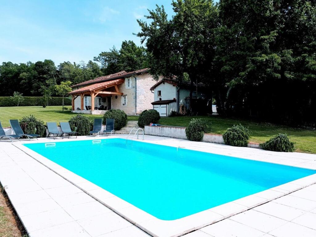 a large blue swimming pool in front of a house at Holiday home with pool in Verteillac in Verteillac