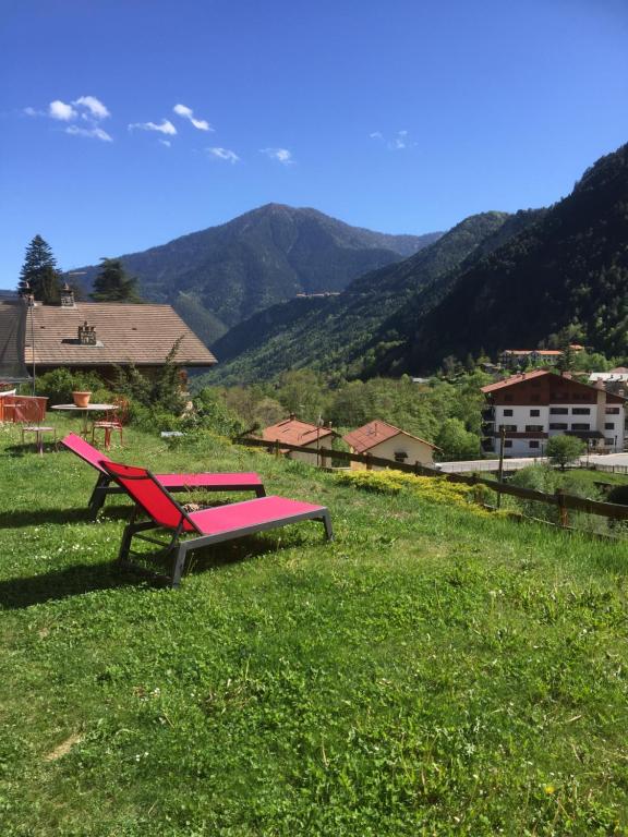 un banc rouge assis dans un champ d'herbe verte dans l'établissement Rez de jardin de chalet bois , calme et verdure !, à Saint-Martin-Vésubie