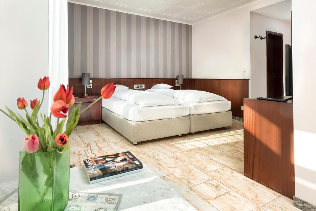 1 dormitorio con 1 cama y un jarrón de flores en Hotel Harheimer Hof, en Frankfurt