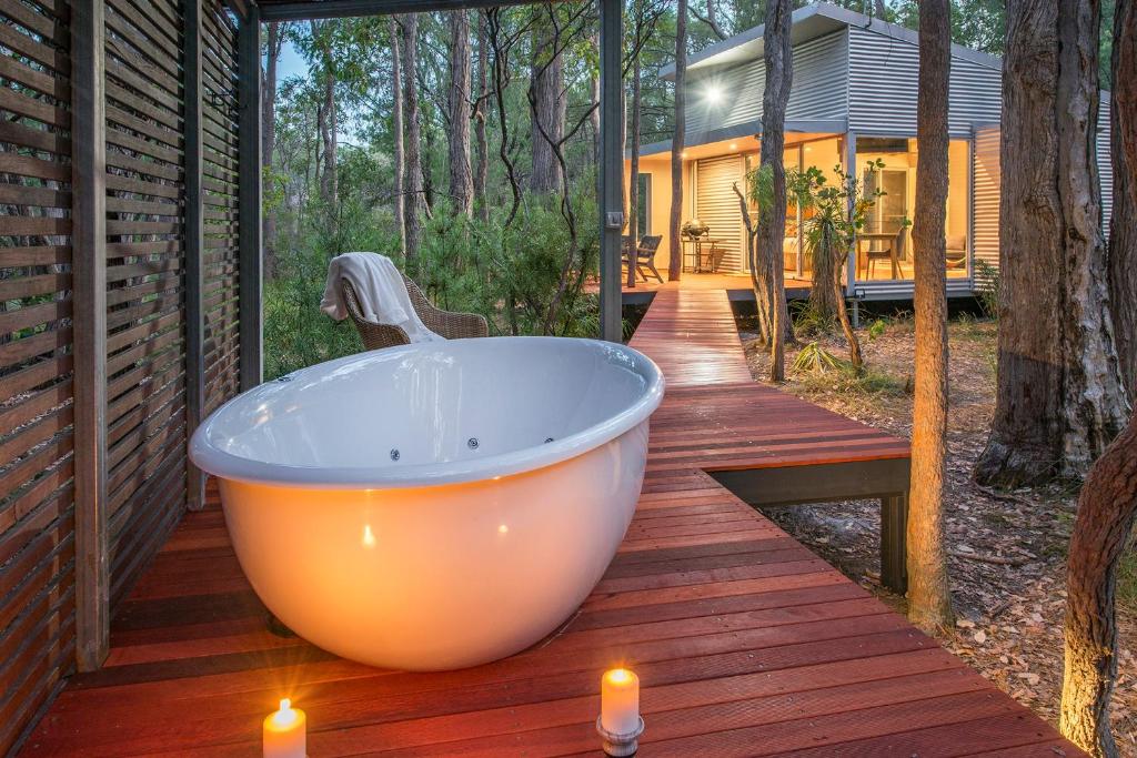 una bañera grande en una terraza con velas en Hidden Valley Forest Retreat en Carbunup