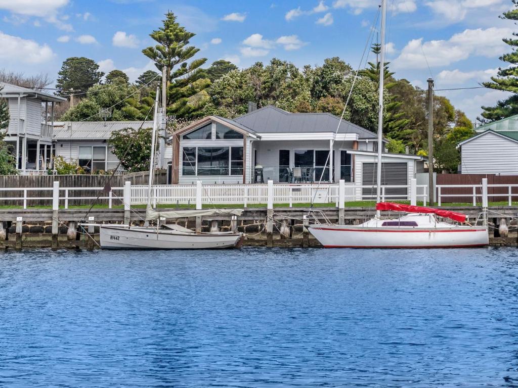 two boats docked at a dock in front of a house at Wisharts Landing in Port Fairy