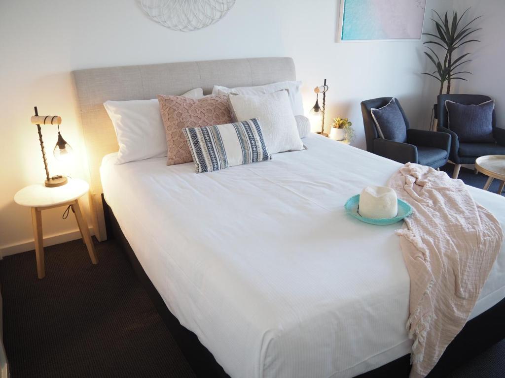 華納灣的住宿－海濱大道汽車旅館，一间卧室配有一张白色的床,上面有蓝色的盘子