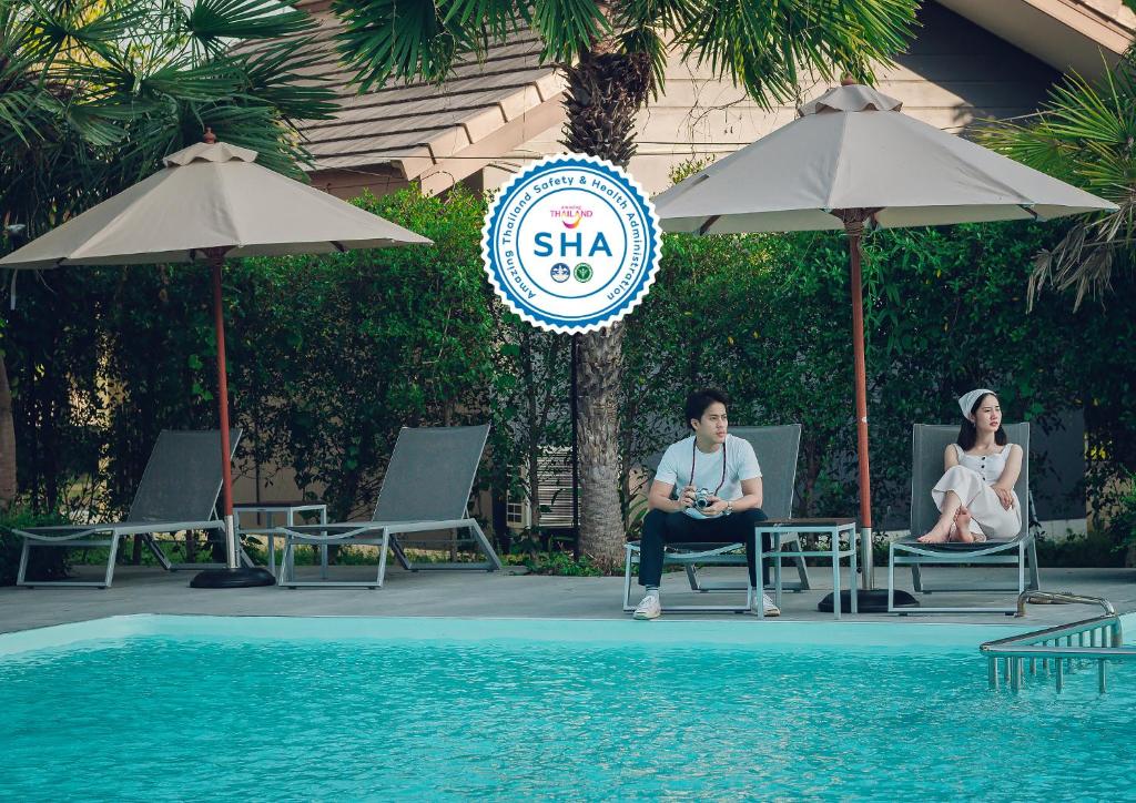 Ein Mann und eine Frau, die auf Stühlen neben einem Pool sitzen in der Unterkunft Chanalai Resort and Hotel in Ban Pa Yang