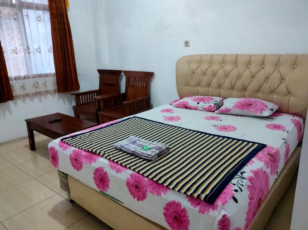 a bedroom with a large bed with pink flowers on it at Hotel Arjuna Sari Bandungan in Bandungan