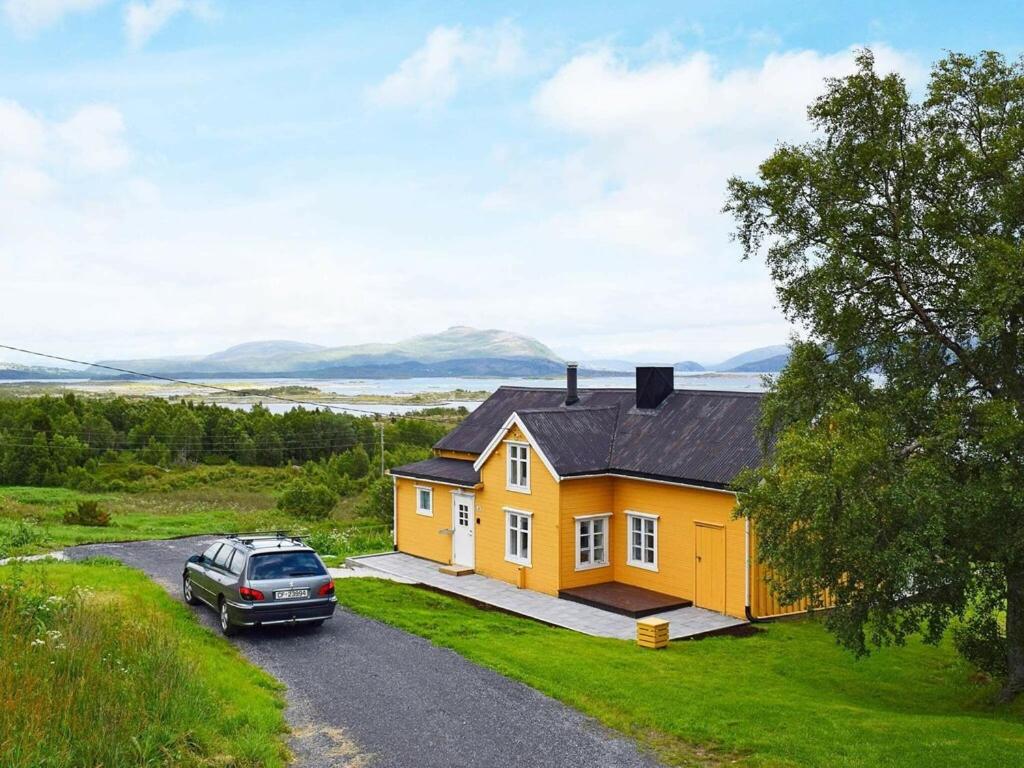 uma casa amarela com um carro estacionado na garagem em 5 person holiday home in Skutvik em Skutvika