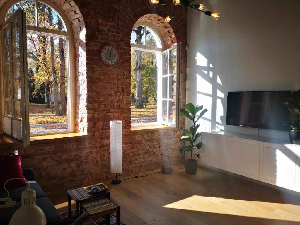 sala de estar con 2 ventanas y TV de pantalla plana en Botanical Garden Studio, en Kaunas