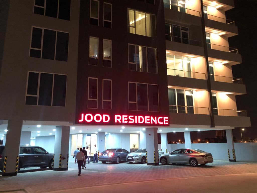 a person walking in front of a hotel at night at JOOD RESIDENCE in Seef